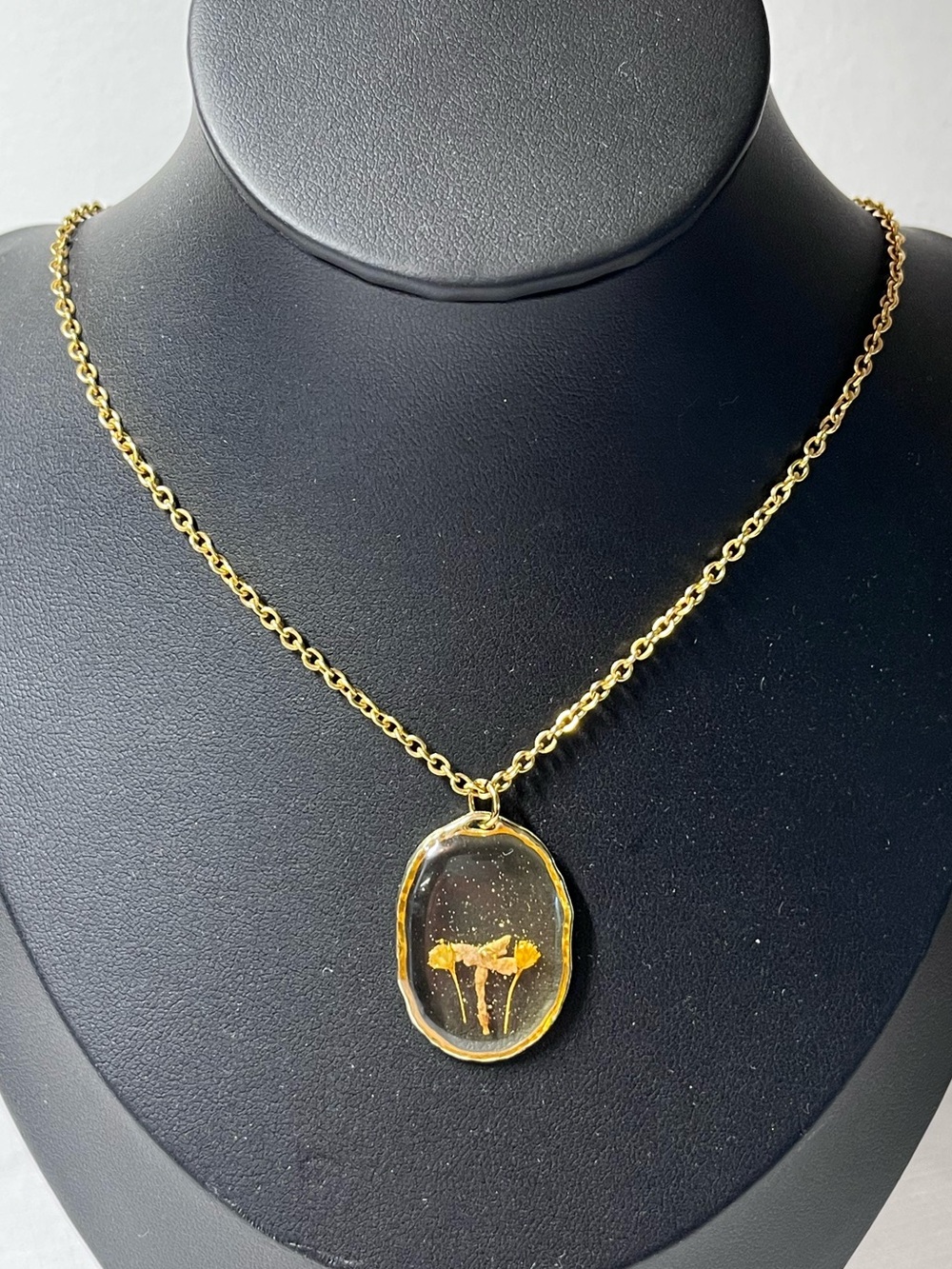 Gold-toned chain necklace
Oval resin pendant
dried flowers